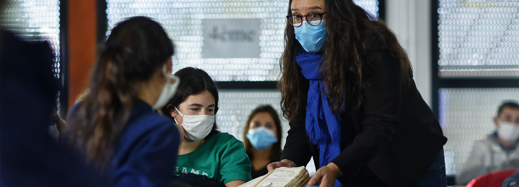 Une archiviste du Département fait découvrir un document à des collégiens.