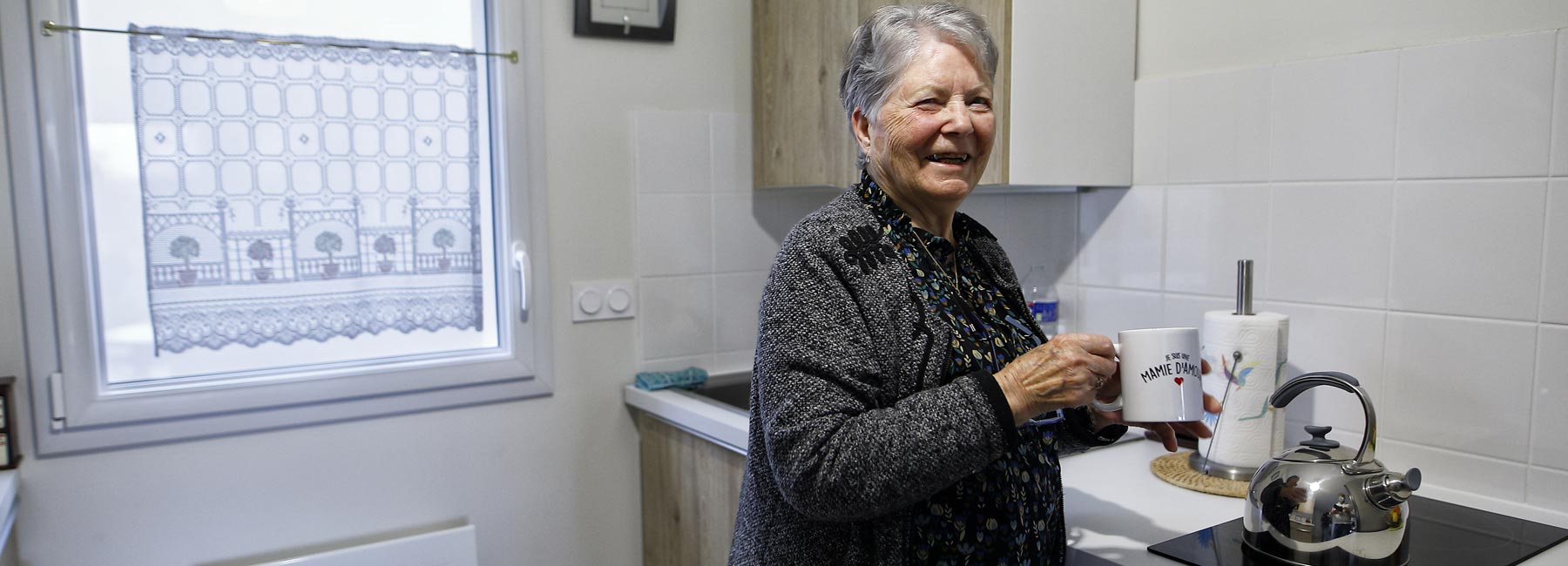 Personne âgée dans sa cuisine, un mug à la main