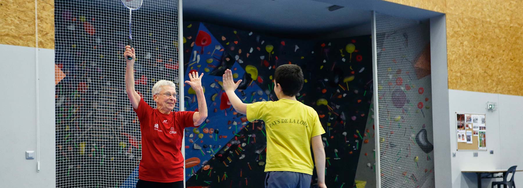Sport intergénérationnel : un adolescent joue au badminton avec une retraitée.