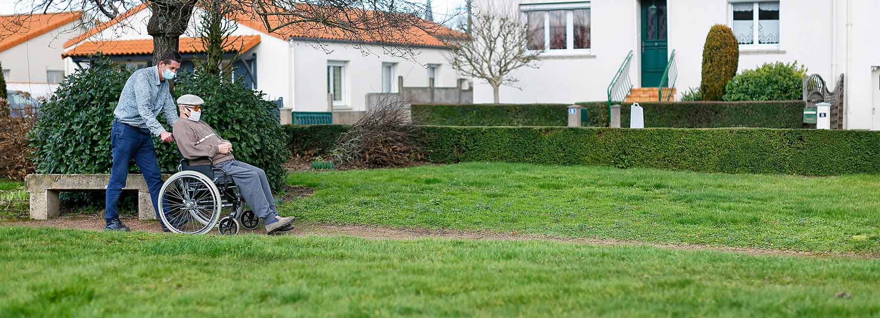 Personne âgée en fauteuil roulant lors d'une balade avec un accompagnant