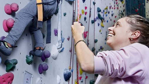 Une femme souriante assure un petit garçon à l'escalade